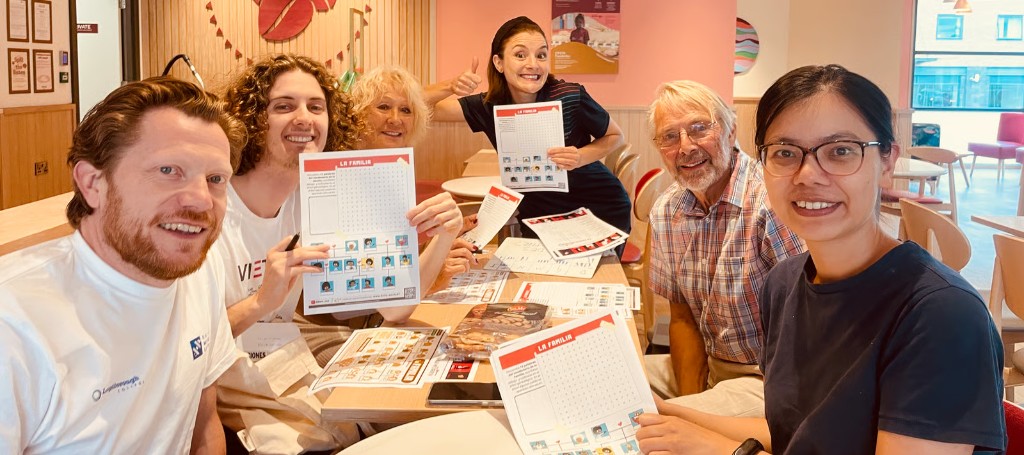 Students smiling with Spanish family vocabulary worksheets at a group class in Loughborough